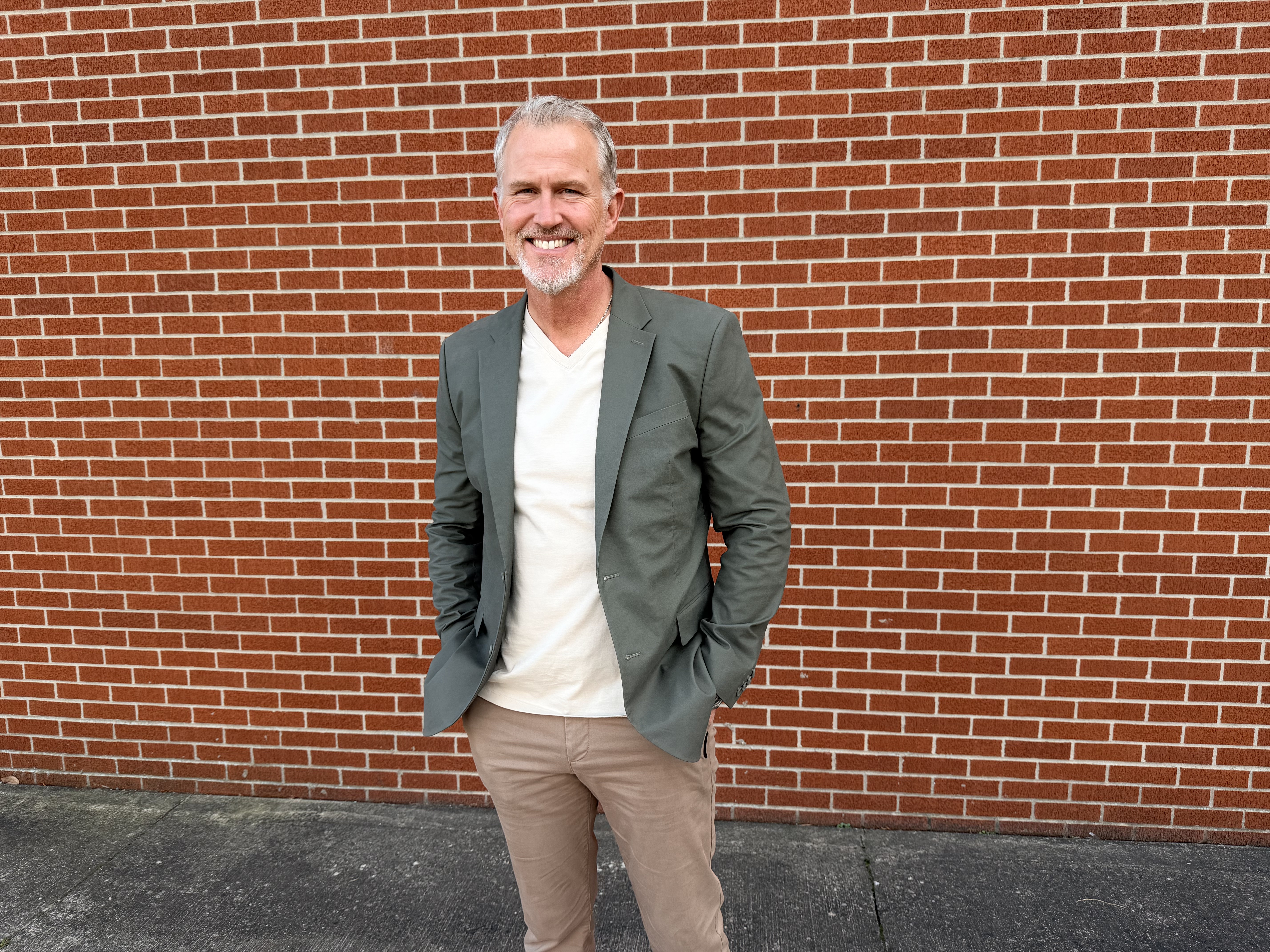 man in a sportscoat standing in front of a brick wall 