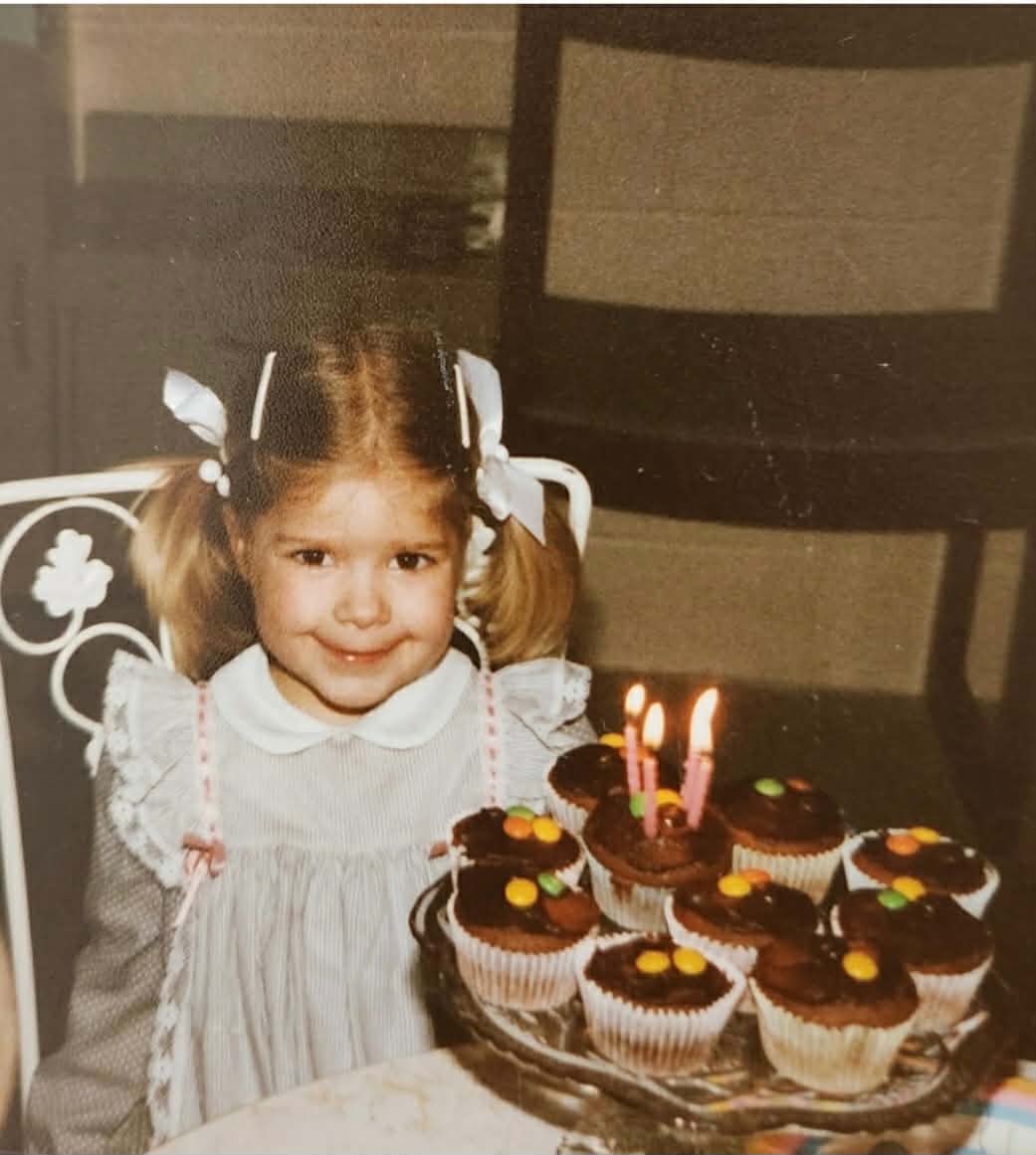 Mary Zack on her fourth birthday with a tray of chocolate cupcakes 