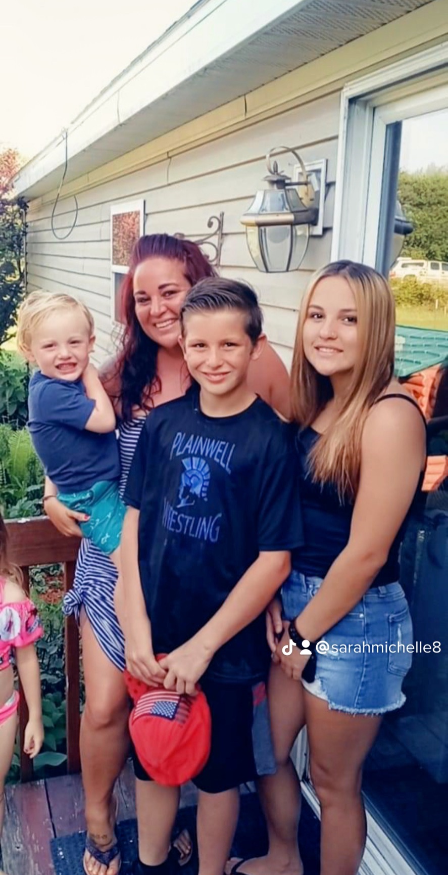 Danyel and three children standing on a porch. 