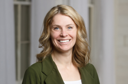 Cinthia smiling at the camera in a dark green blazer 