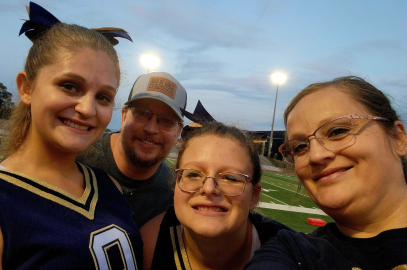 family of four in sports gear smiles at an outdoor field event