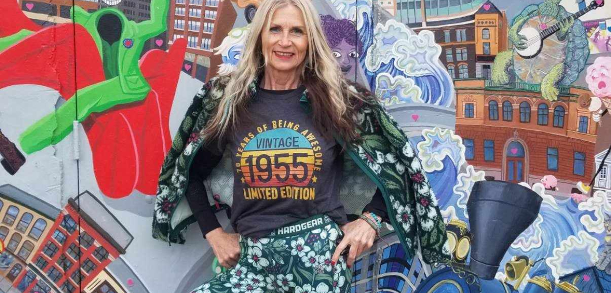 Woman standing in front of a colorful mural.