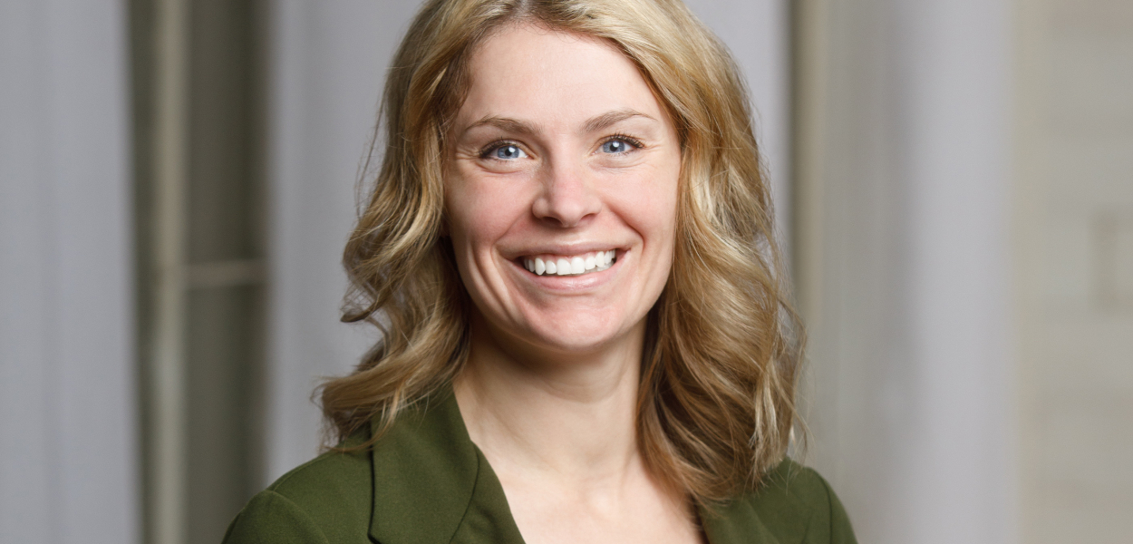 Cinthia smiling at the camera in a dark green blazer 