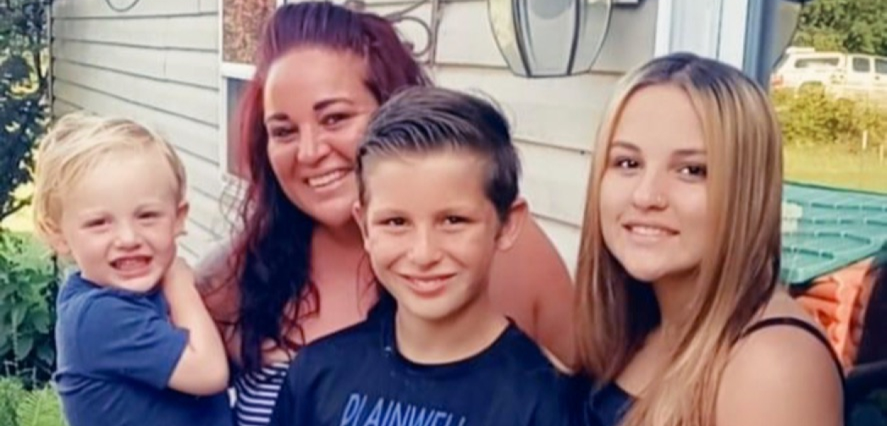 Danyel and three children standing outside on a porch.