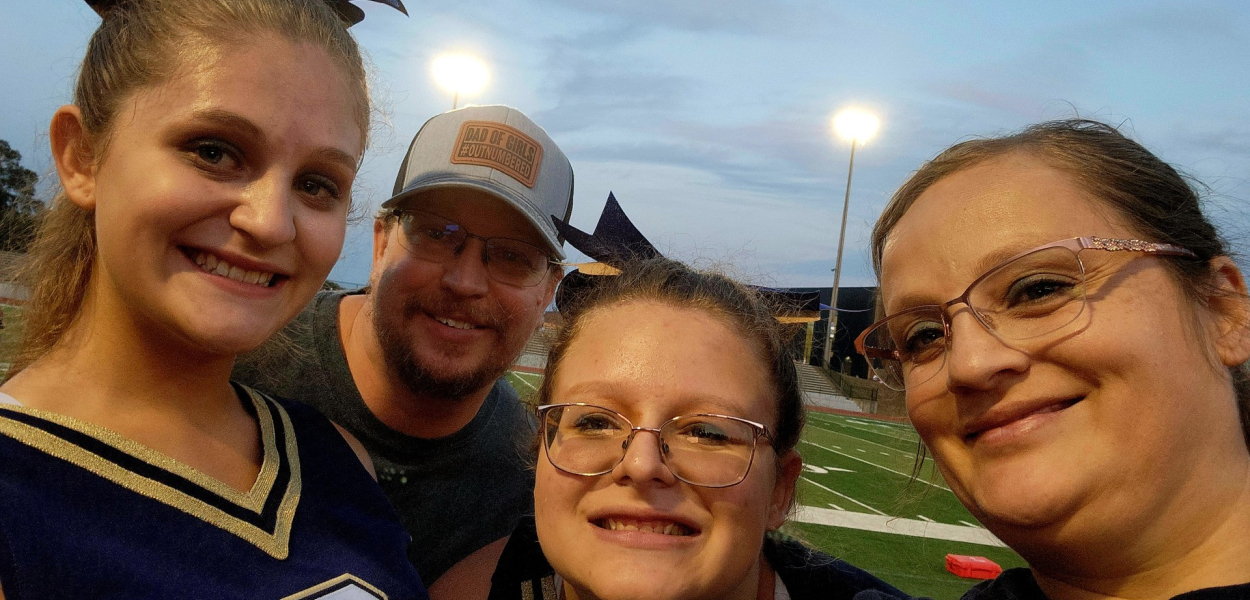 family of four in sports gear smiles at an outdoor field event