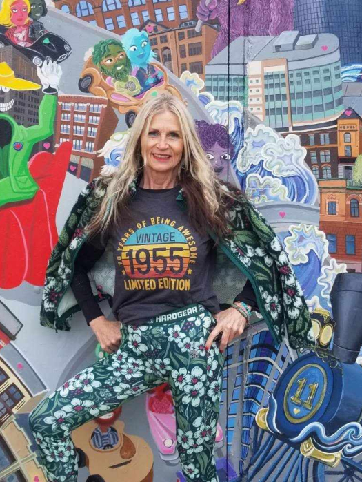 Woman standing in front of a colorful mural.