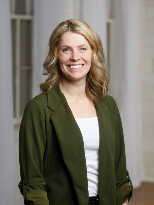 Cinthia smiling at the camera in a dark green blazer 