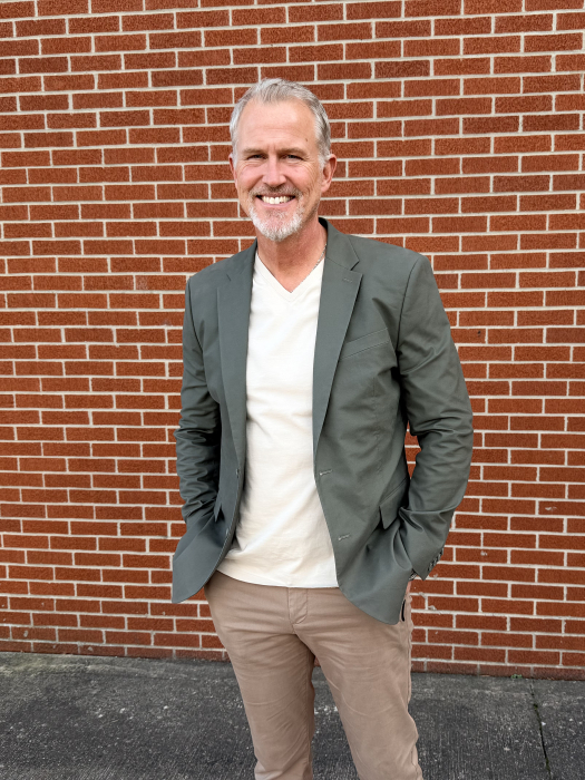 man in sports coat standing in front of a brick wall 