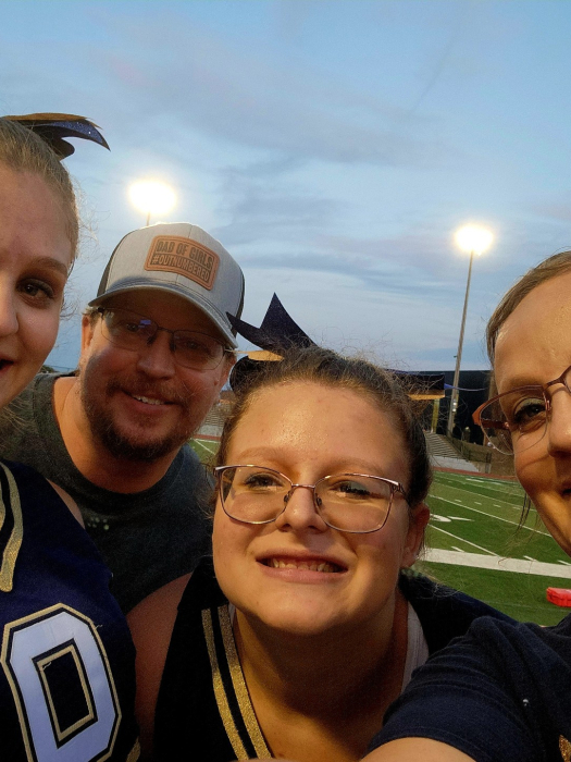 family of four in sports gear smiles at an outdoor field event