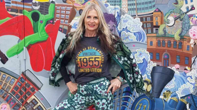 Woman standing in front of a colorful mural.