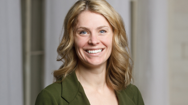 Cinthia smiling at the camera in a dark green blazer 
