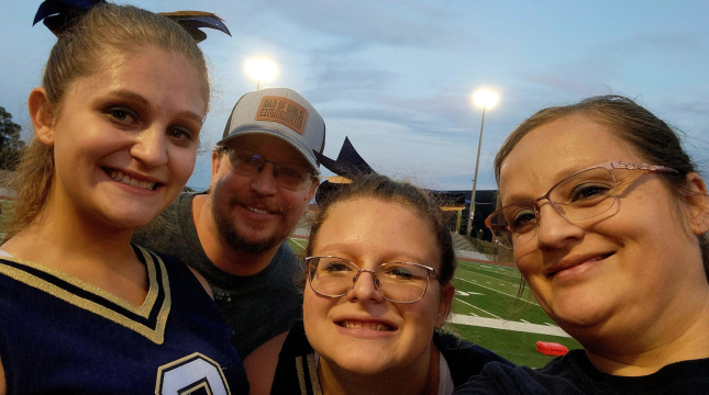 family of four in sports gear smiles at an outdoor field event